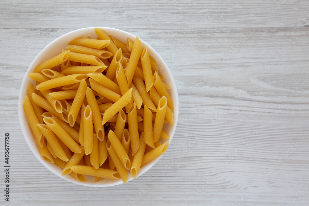 Homemade Raw Dry Penne Pasta in a White Bowl, top view. Flat lay, overhead, from above. Space for text. Homemade Raw Dry Penne Pasta in a White Bowl, top view. Flat lay, overhead, from above. Space for text.