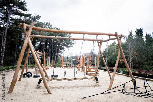 Playground in the forest, colorful children's toys in the park, swing, slide, wooden toys. Selective focus.