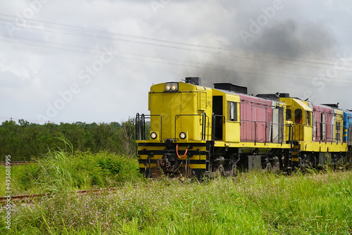 Diesel locomotive with black smoke clouds. It is pulling a heavy freight train with loaded tanks across the northeast of Brazil. Brazilian state of Maranhao, Brazil.