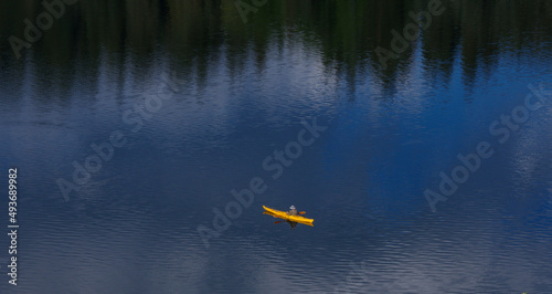 yellow boat with fisherman reflection of boat in water