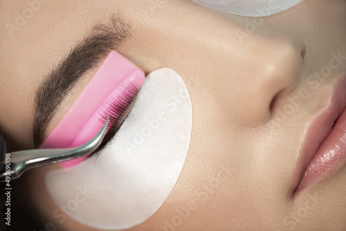 Master glues eyelashes to pink lash roller. Close-up of beauty model\'s face during lash lift laminating botox procedure. Eyelash Care Treatment: eyelash lifting and curling, lash lamination