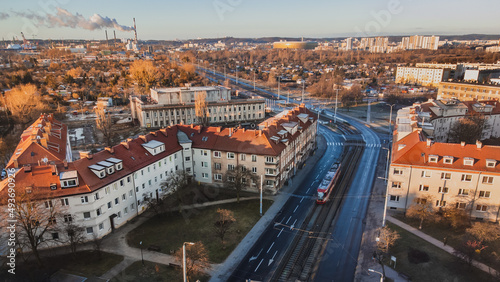 Marynarki Polskiej Street with tram tracks and a running tram. In the background the stadium. Winter morning. View from the drone.