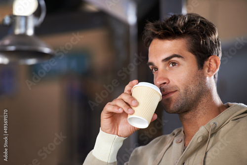 Getting my daily dose of coffee. Shot of a handsome young man drinking a coffee in a cafe.