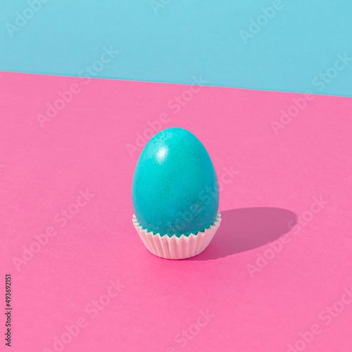 Cyan Easter egg against bold pink and cyan background. Minimal Easter concept. Fun food idea.