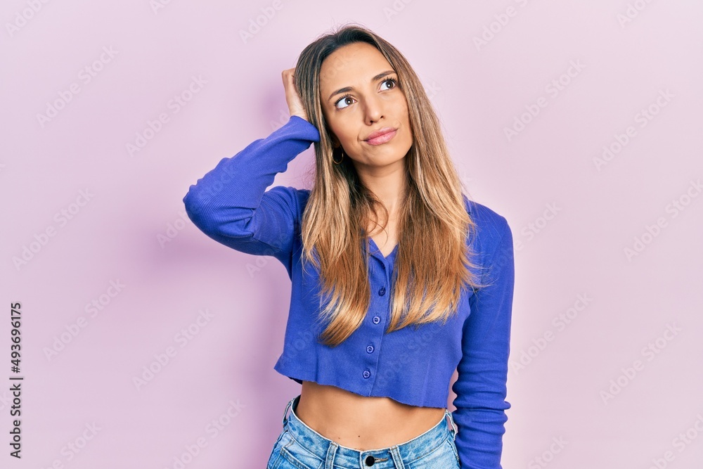 Fototapeta premium Beautiful hispanic woman wearing casual blue shirt confuse and wondering about question. uncertain with doubt, thinking with hand on head. pensive concept.
