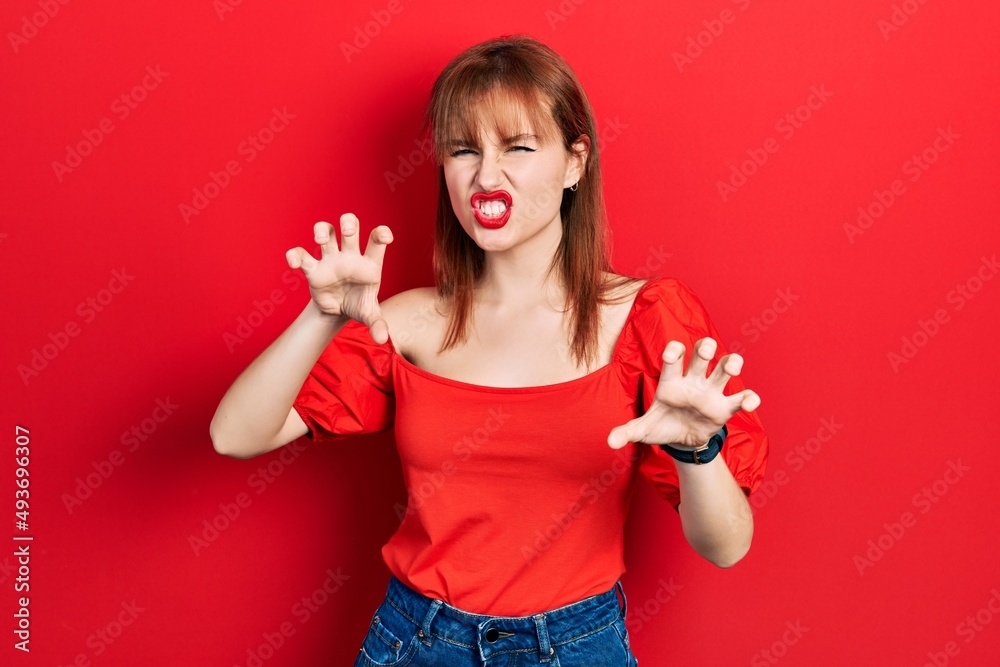 Redhead young woman wearing casual red t shirt smiling funny doing claw gesture as cat, aggressive and sexy expression Redhead young woman wearing casual red t shirt smiling funny doing claw gesture as cat, aggressive and sexy expression