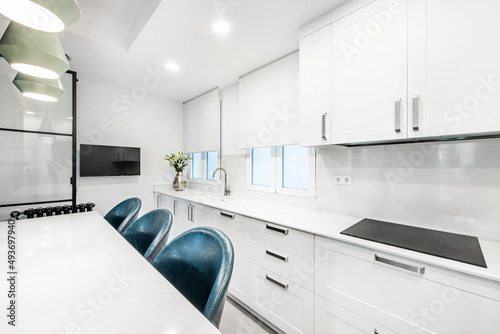 Kitchen of an apartment with black wooden furniture combined with white  large ceramic hob  oak parquet floors and large windows