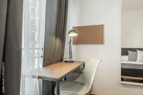 Study tables with a white chair, a black lamp and a mirror on the wall in a bedroom © Toyakisfoto.photos