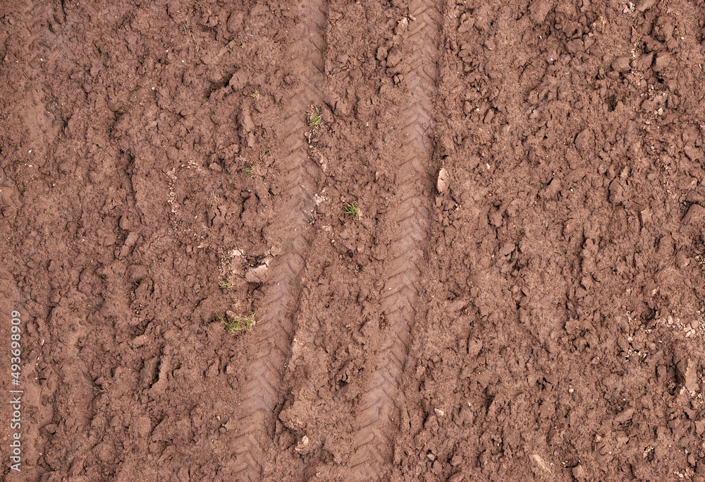 Trilhos das rodas de um trator marcados na terra de um campo lavrado Trilhos das rodas de um trator marcados na terra de um campo lavrado