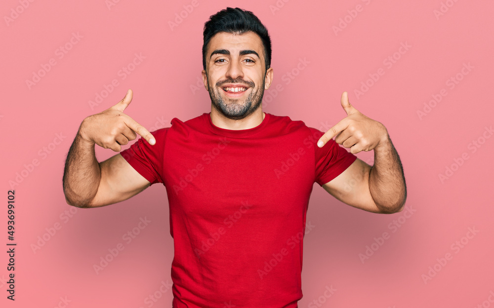 Hispanic man with beard wearing casual red t shirt looking confident with smile on face, pointing oneself with fingers proud and happy. Hispanic man with beard wearing casual red t shirt looking confident with smile on face, pointing oneself with fingers proud and happy.