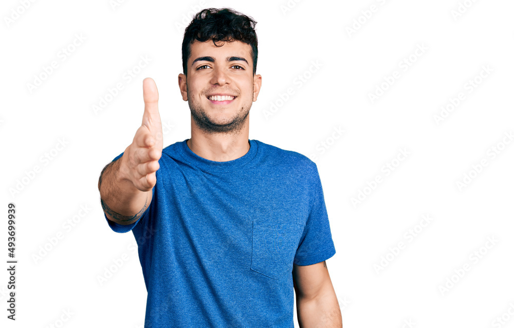 Young hispanic man wearing casual t shirt smiling friendly offering handshake as greeting and welcoming. successful business. Young hispanic man wearing casual t shirt smiling friendly offering handshake as greeting and welcoming. successful business.
