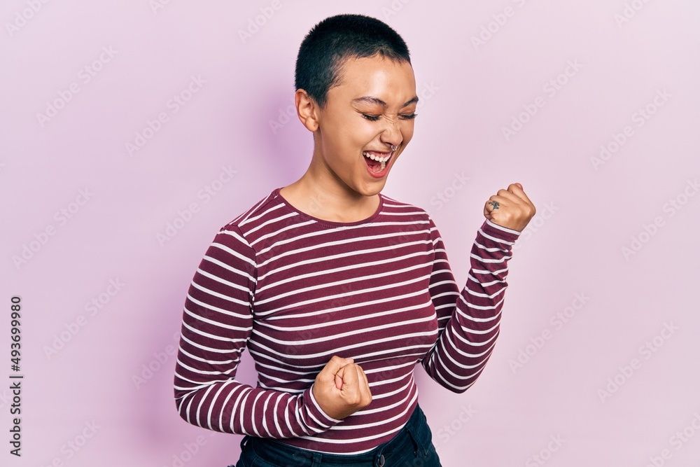 Beautiful hispanic woman with short hair wearing casual striped sweater celebrating surprised and amazed for success with arms raised and eyes closed Beautiful hispanic woman with short hair wearing casual striped sweater celebrating surprised and amazed for success with arms raised and eyes closed