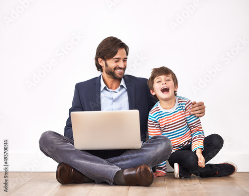 Enjoying some funny online videos. A father and son sitting on the floor with a laptop.