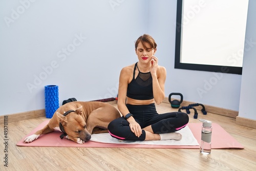 Young beautiful woman sitting on yoga mat touching mouth with hand with painful expression because of toothache or dental illness on teeth. dentist concept.