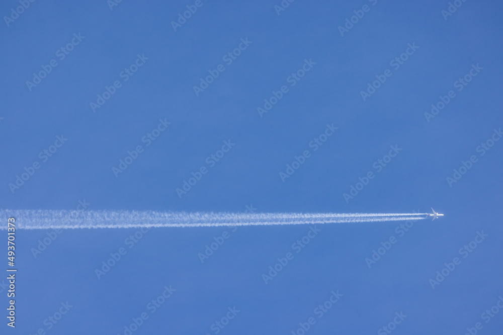 Passenger airplane and contrails against clear blue sky Passenger airplane and contrails against clear blue sky