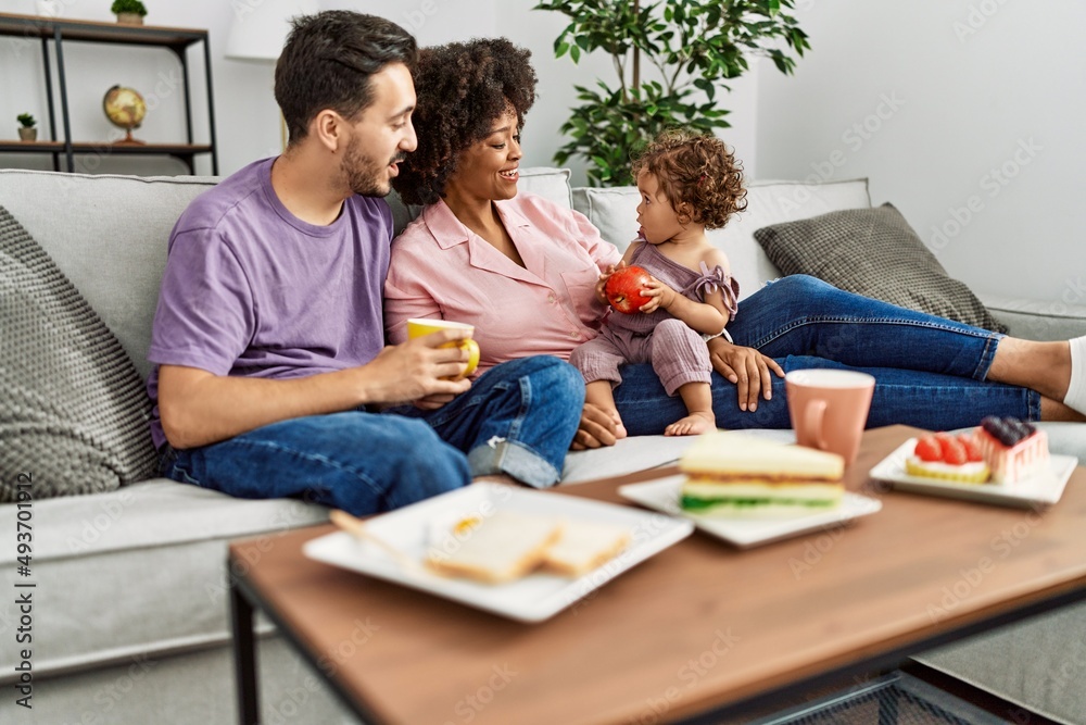 Couple and daughter having breakfast sitting on sofa at home Couple and daughter having breakfast sitting on sofa at home