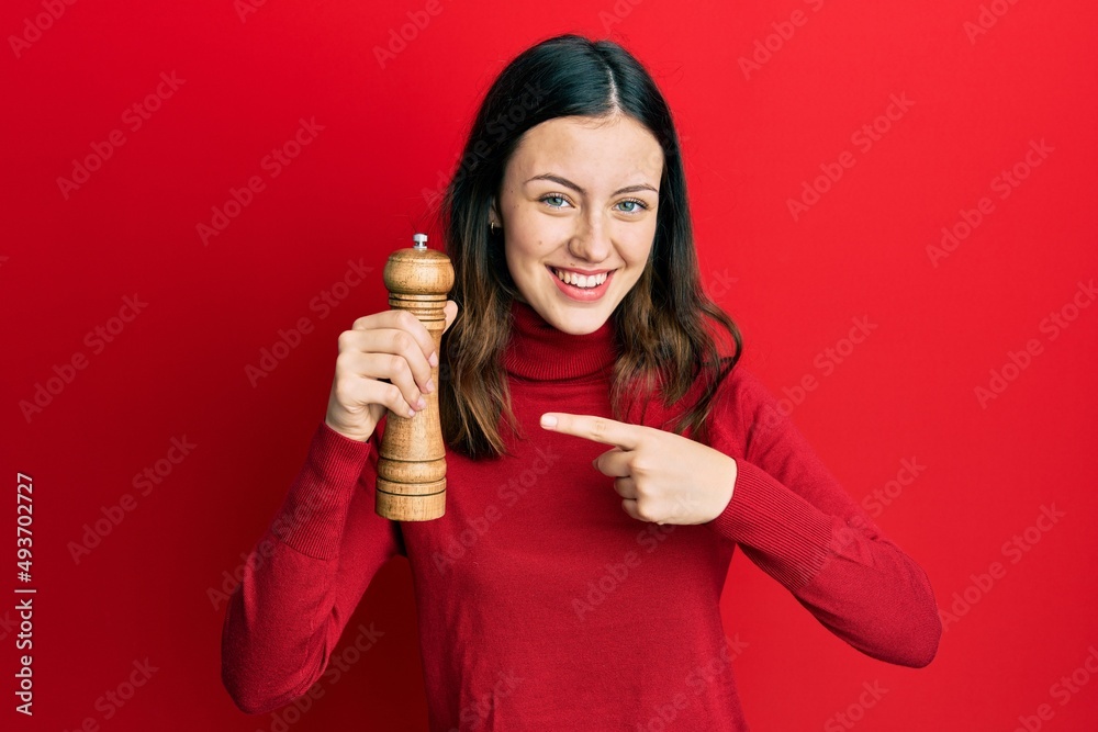 Young brunette woman black pepper grinder smiling happy pointing with hand and finger Young brunette woman black pepper grinder smiling happy pointing with hand and finger