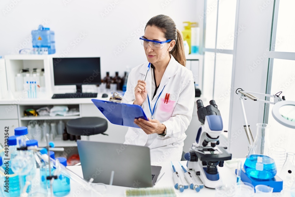 Young hispanic woman wearing scientist uniform working at laboratory Young hispanic woman wearing scientist uniform working at laboratory