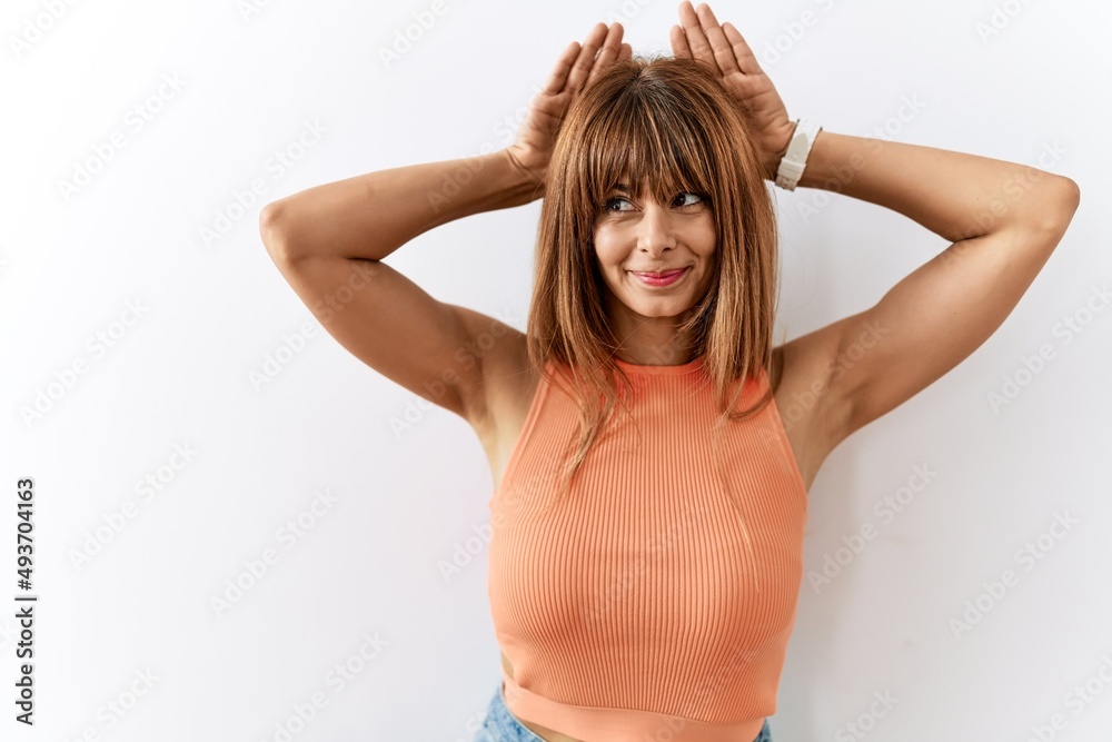 Hispanic woman with bang hairstyle standing over isolated background doing bunny ears gesture with hands palms looking cynical and skeptical. easter rabbit concept.