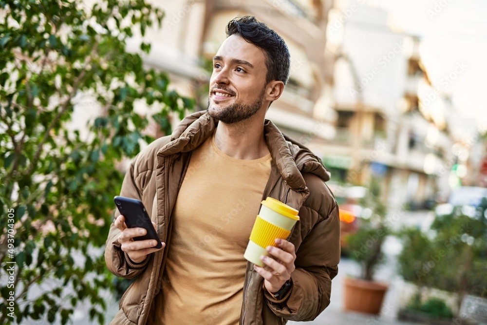 Fototapeta premium Young hispanic man using smartphone drinking coffee at the city.