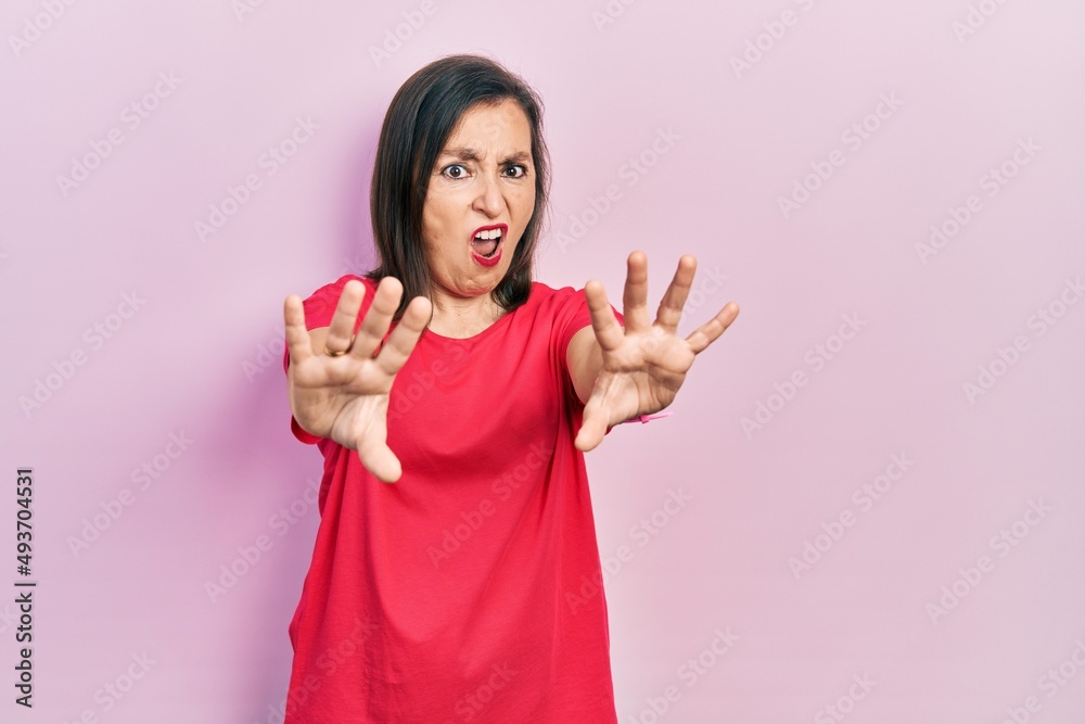 Middle age hispanic woman wearing casual clothes doing stop gesture with hands palms, angry and frustration expression Middle age hispanic woman wearing casual clothes doing stop gesture with hands palms, angry and frustration expression