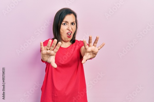 Middle age hispanic woman wearing casual clothes doing stop gesture with hands palms, angry and frustration expression