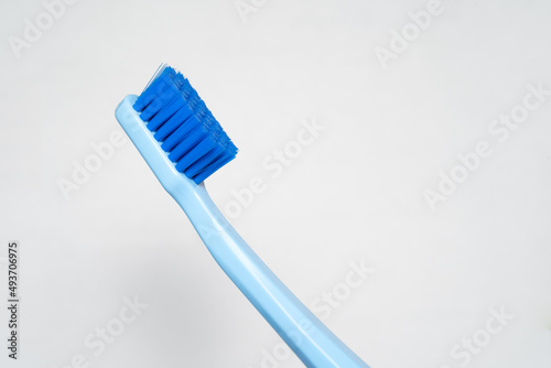 part of blue toothbrush. Toothbrush closeup on white background.