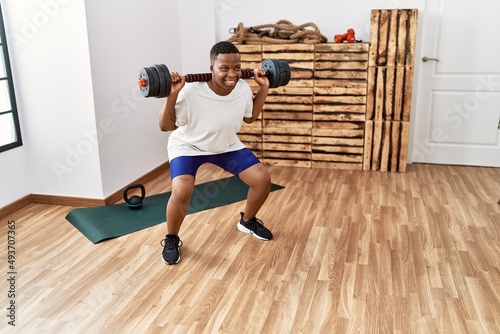 Young african man training with dumbbells at the gym