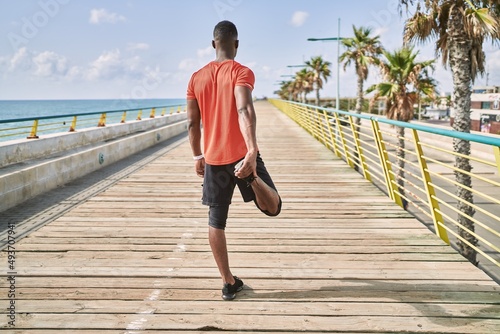 Fototapeta Naklejka Na Ścianę i Meble -  Young african american man wearing sportswear stretching at seaside