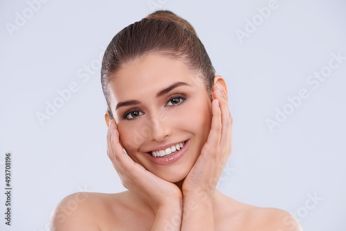 Soft skin makes me smile. Studio portrait of a beautiful young woman posing with her head in her hands.