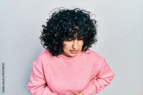 Young middle east woman wearing casual clothes with hand on stomach because indigestion, painful illness feeling unwell. ache concept.