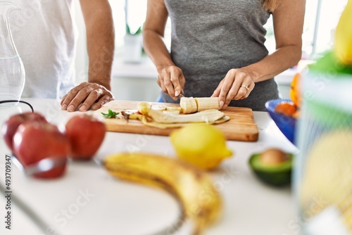 Couple cooking smoothie cutting banana at the kitchen.