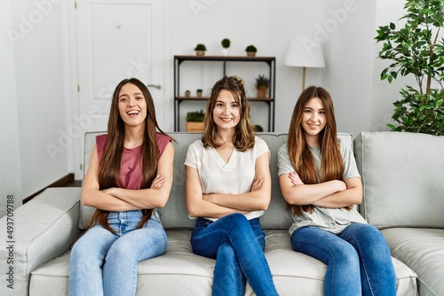 Group of three hispanic girls sitting on the sofa at home happy face smiling with crossed arms looking at the camera. positive person.