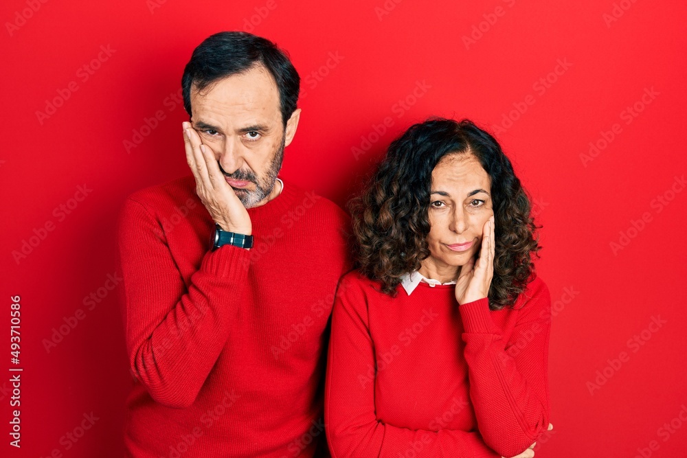 Middle age couple of hispanic woman and man hugging and standing together thinking looking tired and bored with depression problems with crossed arms. Middle age couple of hispanic woman and man hugging and standing together thinking looking tired and bored with depression problems with crossed arms.