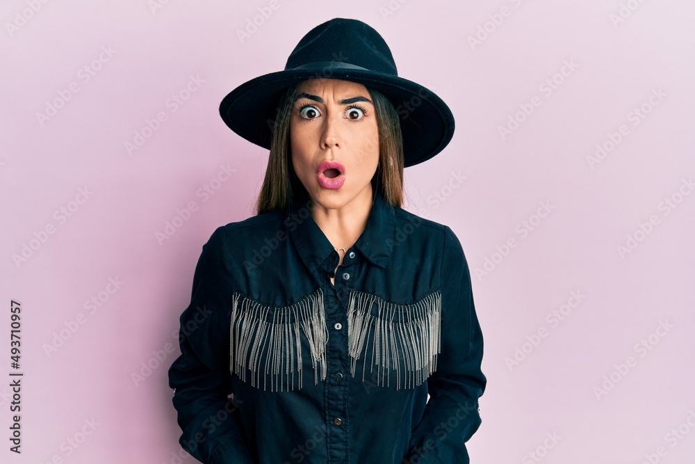 Young hispanic woman wearing cowgirl style scared and amazed with open mouth for surprise, disbelief face Young hispanic woman wearing cowgirl style scared and amazed with open mouth for surprise, disbelief face