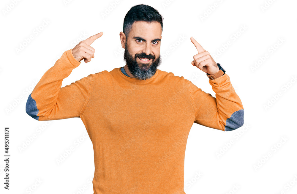 Fototapeta premium Hispanic man with beard wearing casual winter sweater smiling pointing to head with both hands finger, great idea or thought, good memory