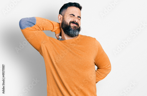 Hispanic man with beard wearing casual winter sweater suffering of neck ache injury, touching neck with hand, muscular pain © Krakenimages.com