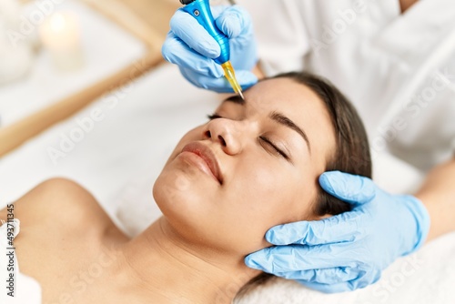 Young latin woman relaxed having microblading eyebrows treatment at beauty center