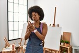 Young african american woman with afro hair at art studio suffering pain on hands and fingers, arthritis inflammation