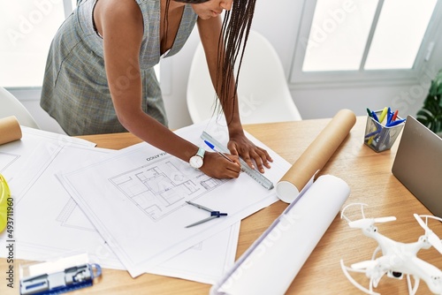 Young african american woman architect writing on house plans at architecture studio
