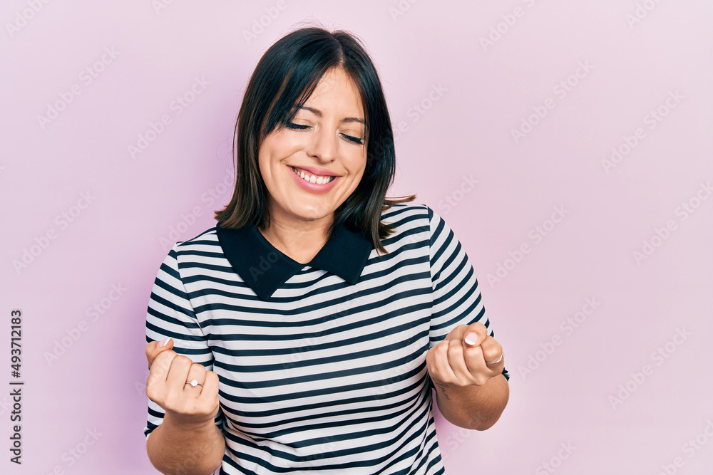 Young hispanic woman wearing casual clothes very happy and excited doing winner gesture with arms raised, smiling and screaming for success. celebration concept. Young hispanic woman wearing casual clothes very happy and excited doing winner gesture with arms raised, smiling and screaming for success. celebration concept.