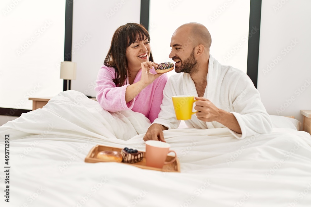 Young hispanic couple having breakfast sitting on the bed at bedroom. Young hispanic couple having breakfast sitting on the bed at bedroom.