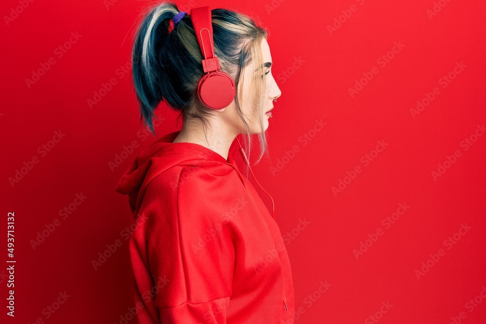 Young modern girl wearing gym clothes and using headphones looking to side, relax profile pose with natural face with confident smile.