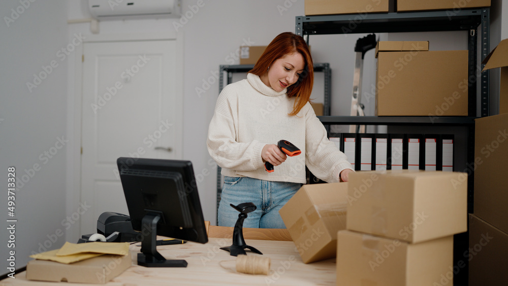 Young redhead woman ecommerce business worker scanning package barcode reader at office Young redhead woman ecommerce business worker scanning package barcode reader at office