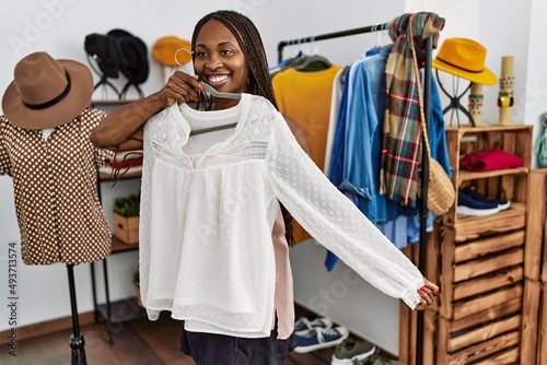 Young african american customer woman smiling happy holding hanger with clothes at clothing store.