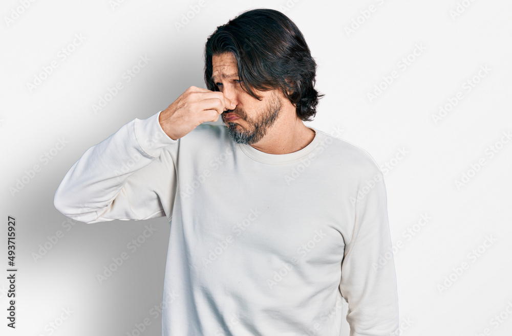 Middle age caucasian man wearing casual clothes smelling something stinky and disgusting, intolerable smell, holding breath with fingers on nose. bad smell Middle age caucasian man wearing casual clothes smelling something stinky and disgusting, intolerable smell, holding breath with fingers on nose. bad smell