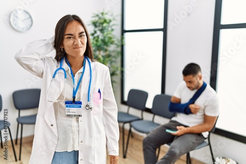 Young asian doctor woman at waiting room with a man with a broken arm confuse and wonder about question. uncertain with doubt  thinking with hand on head. pensive concept.