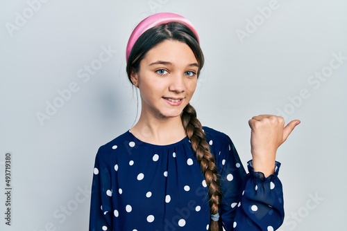 Young brunette girl wearing elegant look smiling with happy face looking and pointing to the side with thumb up.