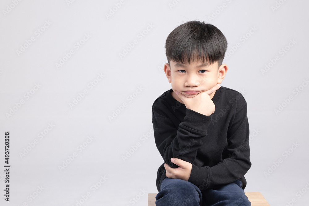 Asian boy with thinking expression. A Kid about 6 years old touching his chin and making curious face. Asian boy with thinking expression. A Kid about 6 years old touching his chin and making curious face.