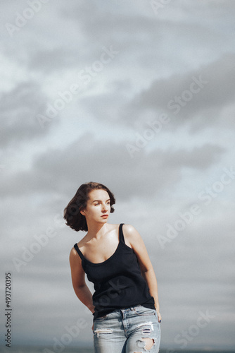 A girl in a black t-shirt walks alone on a sandy beach